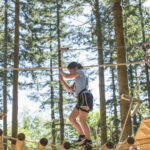 Two visitors cross a log bridge on the Tree Hoppers course at Zip World Fforest, Betws-y-Coed